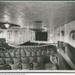 Image: Inside of a theatre hall, view of a front stage overlooking rows of chairs and a balcony