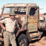 Image: Man leans on rusted truck