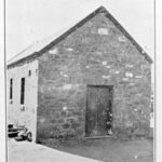 Image: black and white image of stone building with peaked roof.