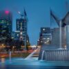 Image: Three Rivers Fountain which is located in Victoria Square, Adelaide.  This photo was taken at night time, with tall buildings in the background.