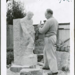 Image: black and white photograph of man sculpting in stone