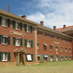 Image: A vey large, three-storey historic brick building with a neo-Classical entry. Two signs with the words ‘Ranson Mortlock Laboratory’ and ‘John Darling Laboratory’ are visible on the side of the building