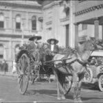 Image: Two women and a child sitting in a buggy drawn by a single horse through a city street