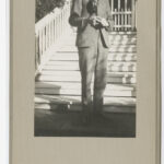 Image: Man standing at the bottom of some stairs holding a magpie