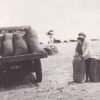 Image: woman standing with large hessian bags next to vehicle loaded with bags